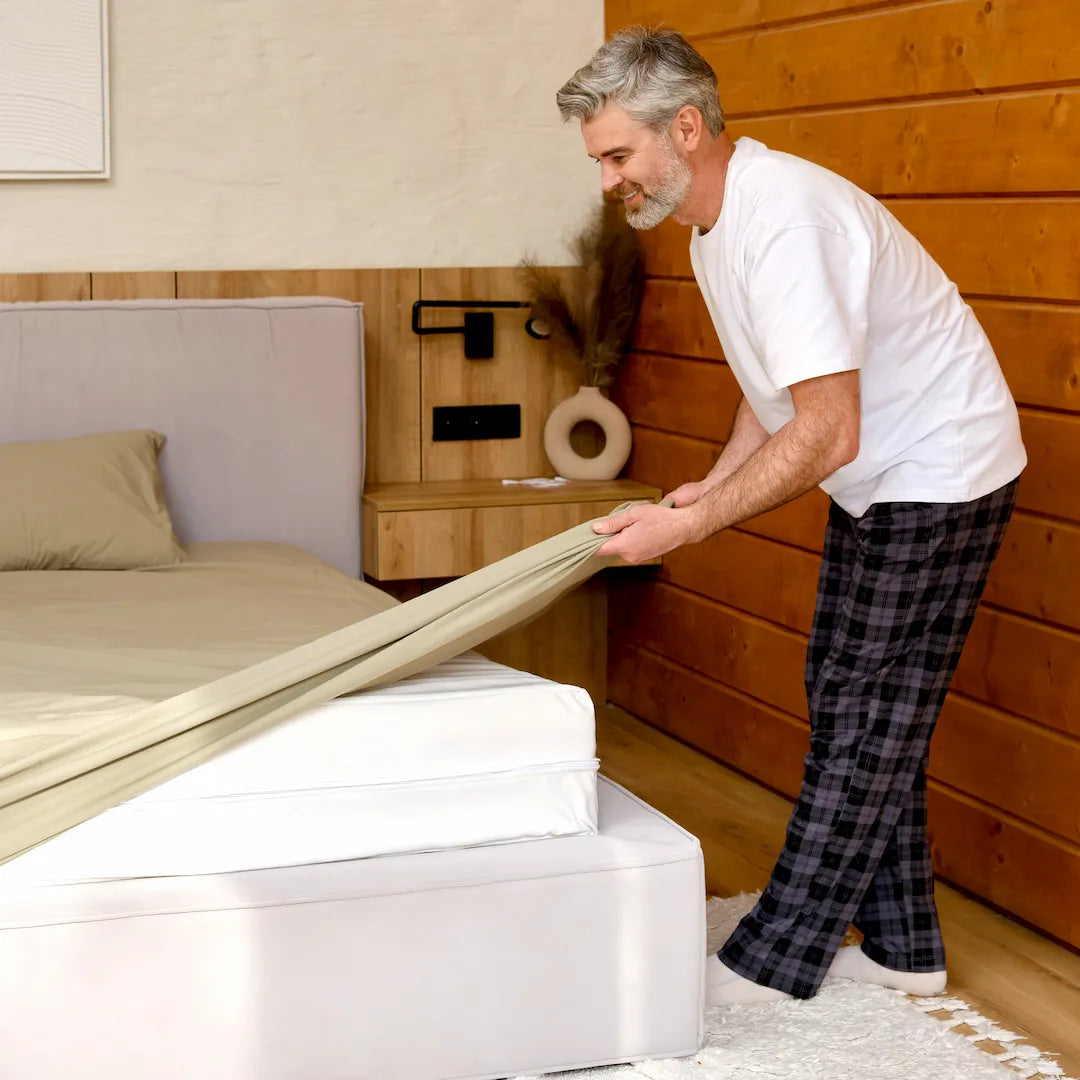 Man putting on grounding sheets on bed