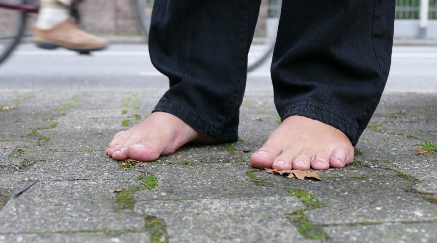 Person standing barefoot in a city on a surface where you can ground yourself