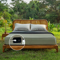 Earthy green grounding fitted sheets on a wooden bed outdoors, demonstrating how earthing can improve overall well-being