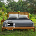 Gray grounding fitted sheets on a wooden bed set in a natural outdoor setting, emphasizing their benefits for enhanced sleep and stress relief