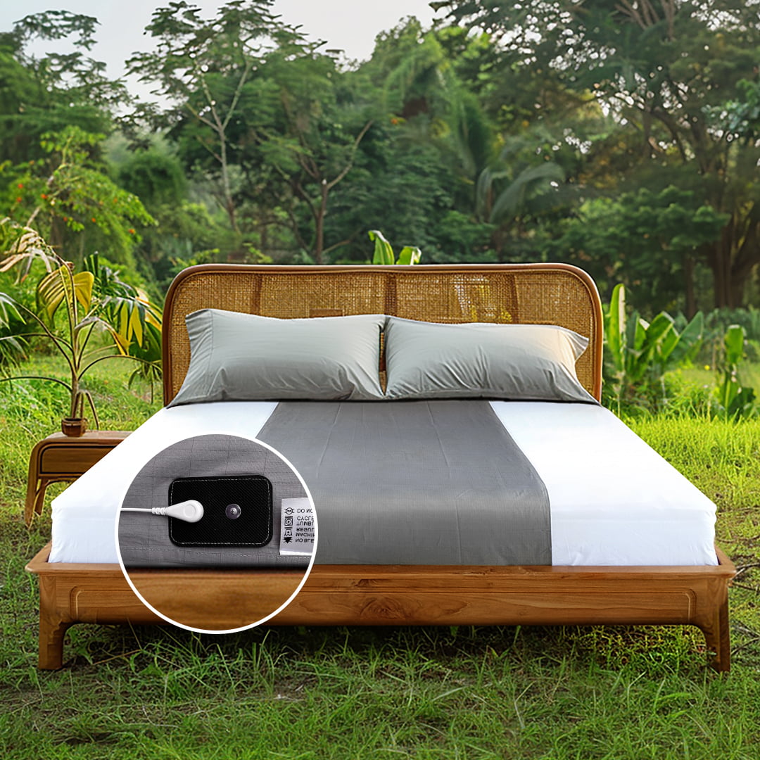 Gray grounding flat half-sheets arranged on a rustic wooden bed outdoors, surrounded by lush greenery, highlighting natural earthing techniques