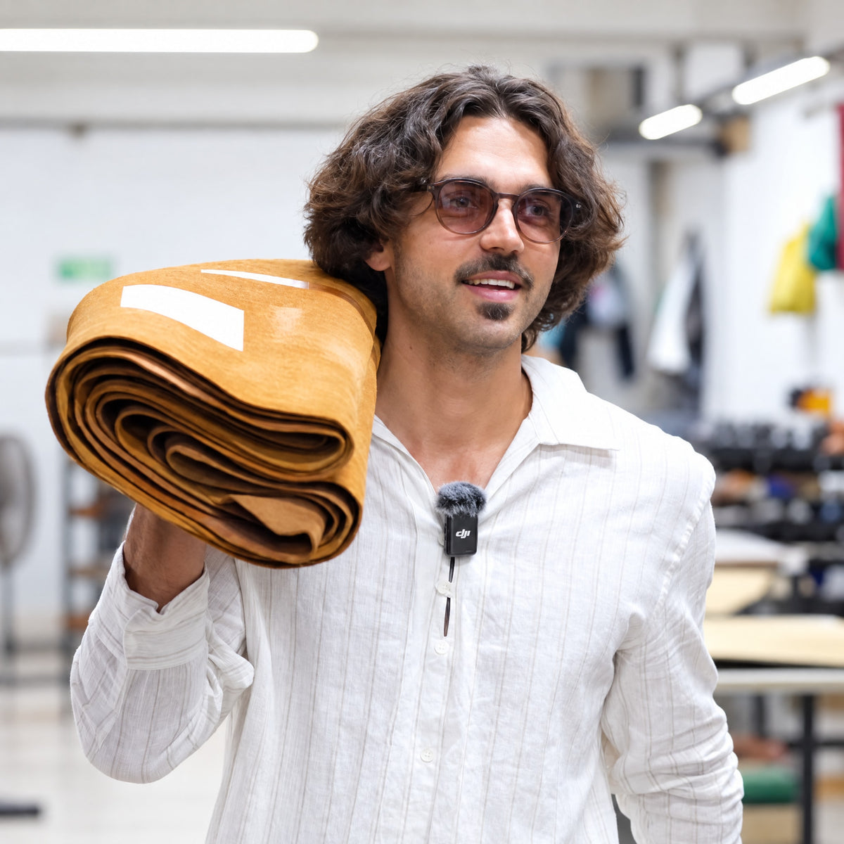 Sander, founder of Earthing Harmony, carrying a roll of leather in the workshop
