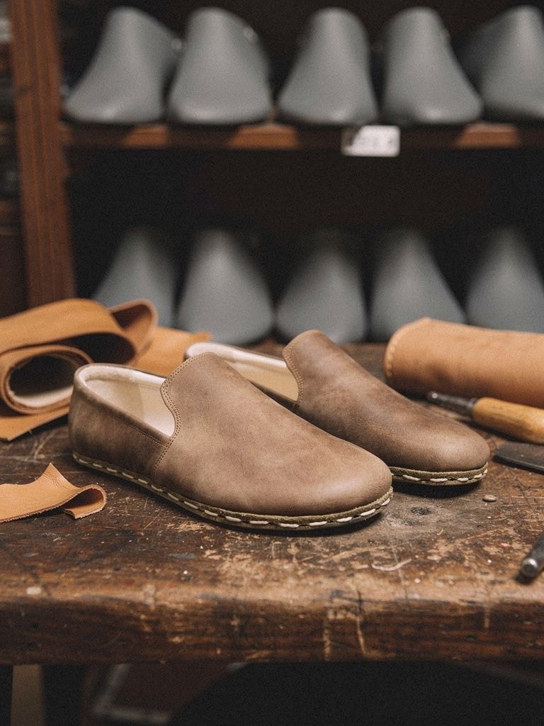 Shoe uppers being stitched to leather soles